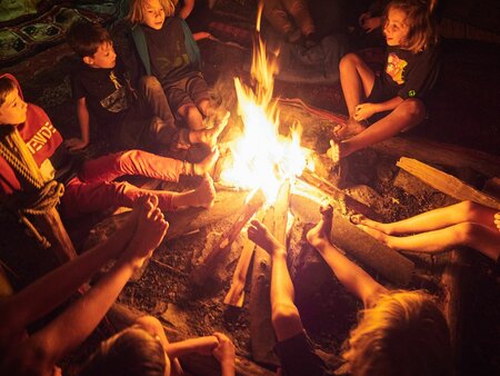 Kinder erleben Gemeinschaft beim Lagerfeuer im ROOTS Naturcamp Österreich