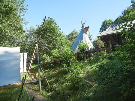 Natur-Camp mit Tipi-Zelt und grünem Wald bei Ferienlager für Kinder